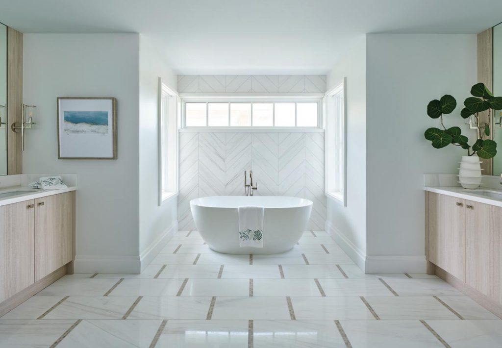 On the home’s upper level, marble tiles in a chevron pattern behind the tub add dimension to the master bath. Photo by Carmel Brantley